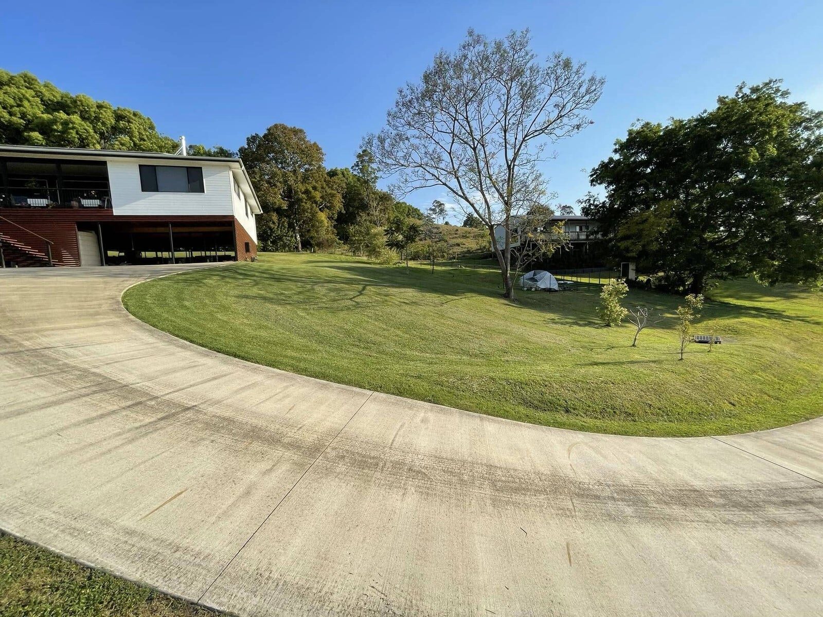 Freshly cleaned sweeping concrete driveway beside a modern country home